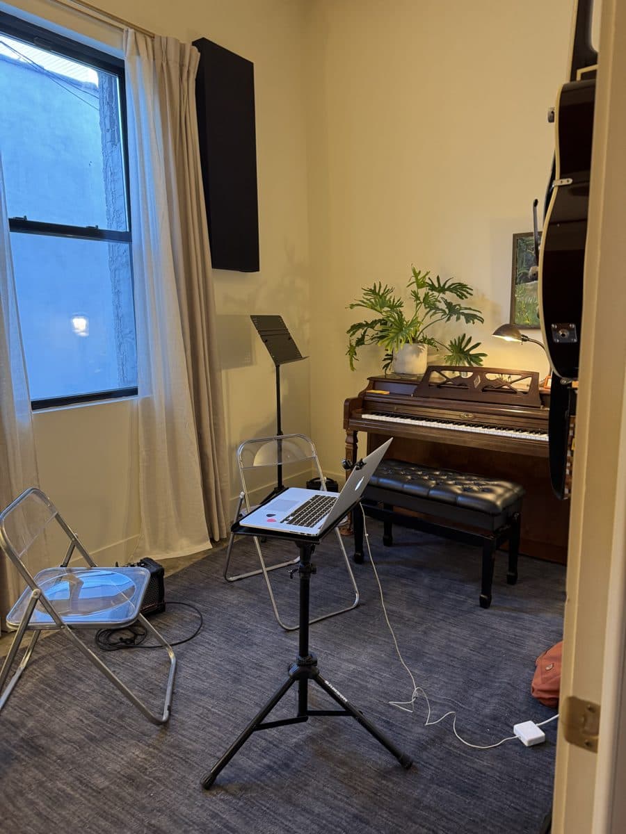 A Rising Stars lesson room with an upright piano, guitars on the wall, and soft window light